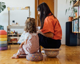 Mama und Kind sitzen auf Stapelstein® confetti Elementen